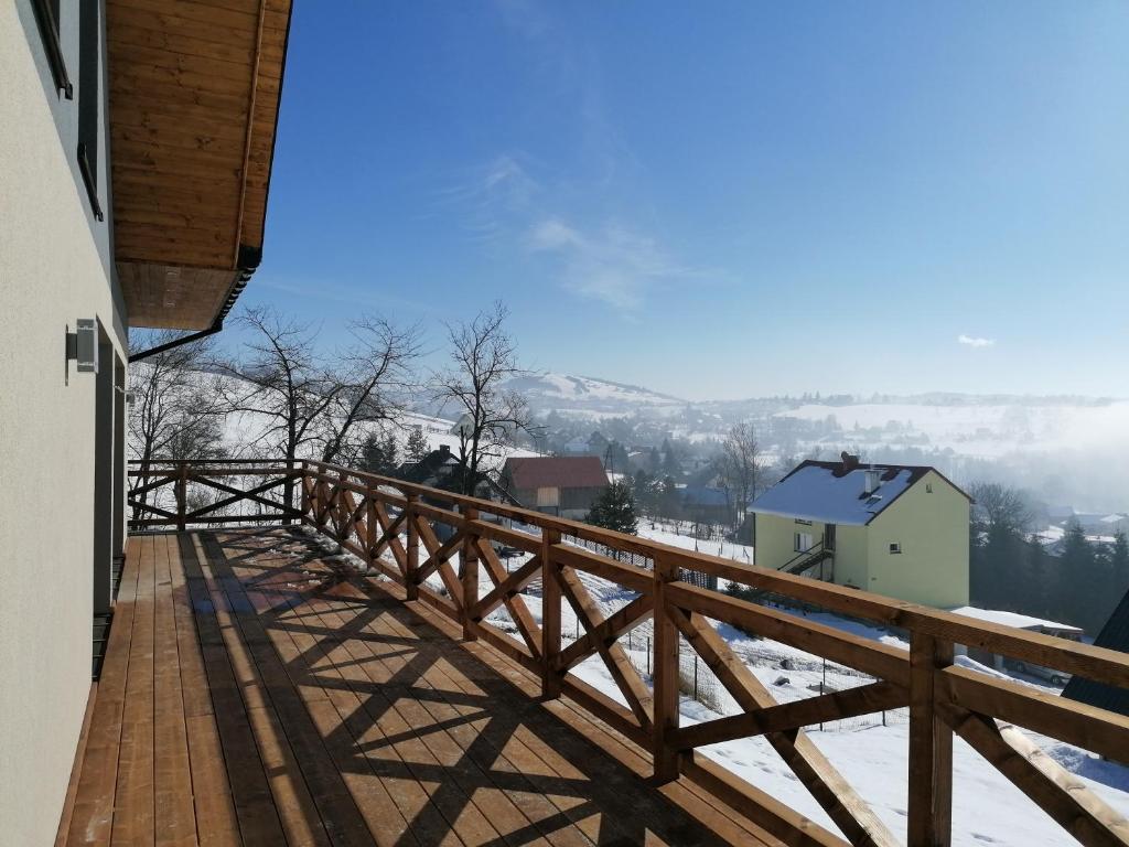 a wooden balcony with a view of the snow covered mountains at Dwie Owce in Istebna