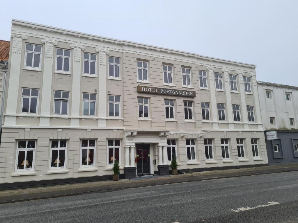 ein großes weißes Gebäude an der Straßenseite in der Unterkunft Hotel Postgaarden in Fredericia