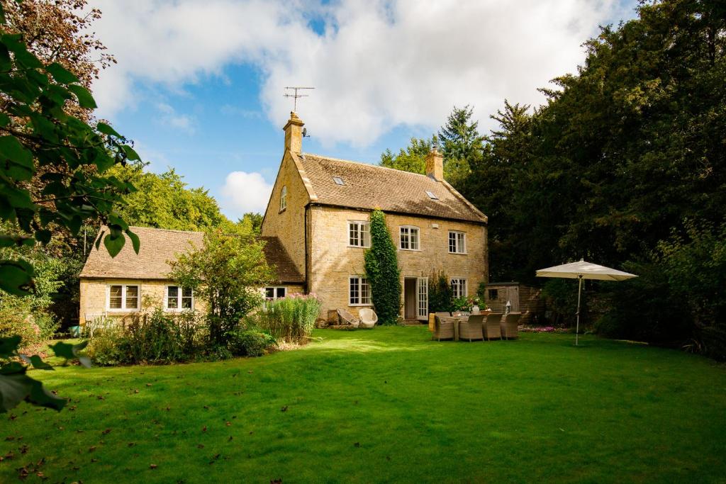 a large stone house with a grass yard at Temple Guiting Cottage in Temple Guiting