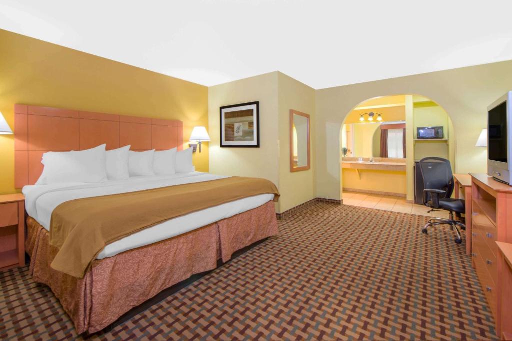 a hotel room with a large bed and a television at Days Inn by Wyndham Lubbock South in Lubbock