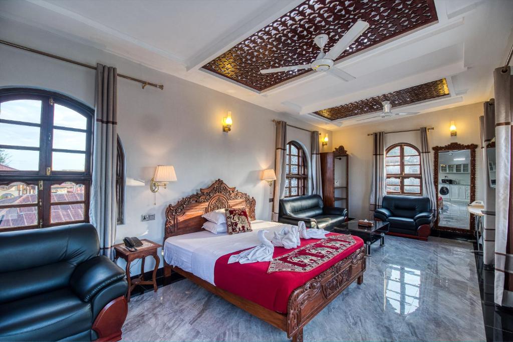 a hotel room with a bed and two chairs at Tembo B&B Apartments in Zanzibar City
