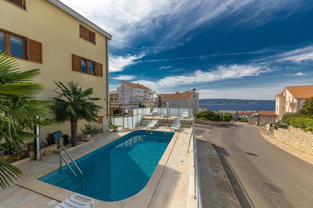 a house with a swimming pool next to a street at Apartments Villa Ivka in Crikvenica