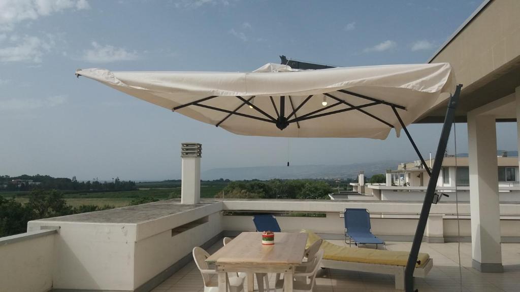 una sombrilla blanca en un balcón con mesa y sillas en Attico Oleandro - Penthouse loft with sea view - Nova Siri, Basilicata, en Nova Siri Marina