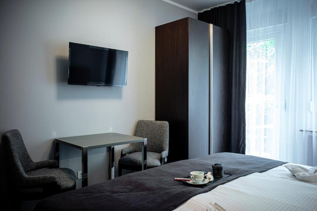 ラーデヴォルムヴァルトにあるLöwen Hotelのベッド、テーブル、テレビが備わる客室です。