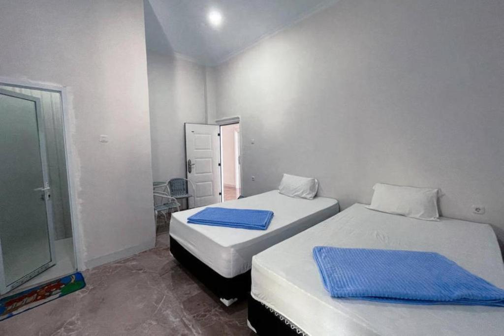 Habitación con 2 camas y toallas azules. en Wisma Maestro Toraja Mitra RedDoorz, en Rantepao