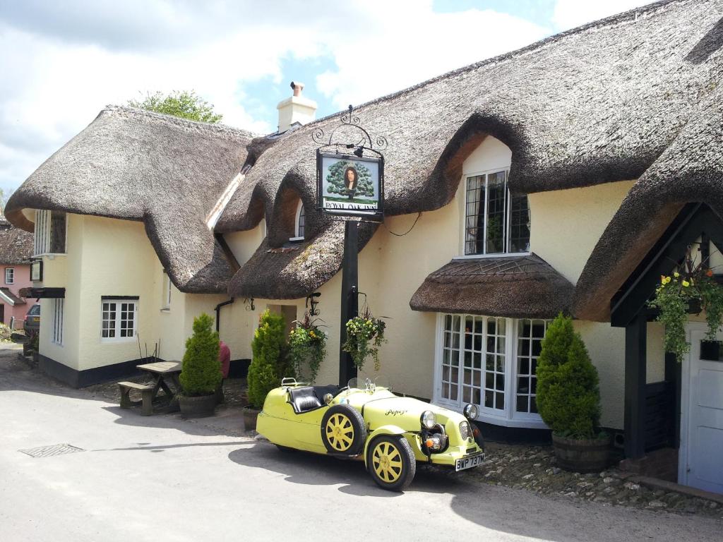 The Royal Oak Exmoor في Winsford: سيارة خضراء متوقفة أمام مبنى من القش