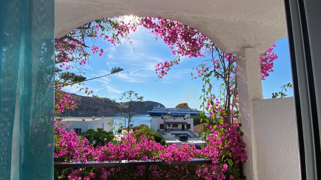 a window with pink flowers and a view of a harbor at Skala Hotel in Skala