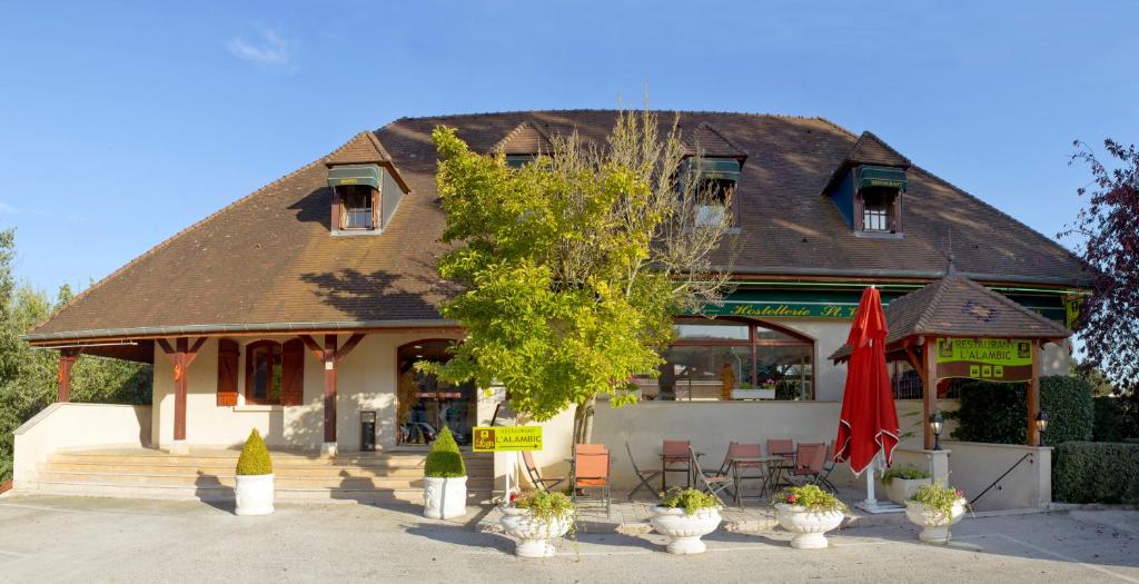 a building with a tree and chairs in front of it at Hostellerie St Vincent in Nuits-Saint-Georges