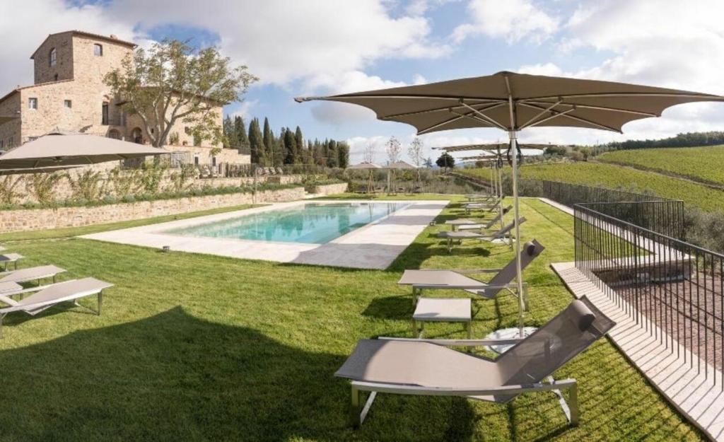 - une piscine avec des chaises et un parasol à côté d'un bâtiment dans l'établissement Villa Torre Greve, à Greve in Chianti