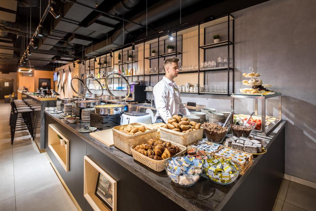 a man standing behind a counter in a kitchen with food at B&B Hotel Budapest City in Budapest