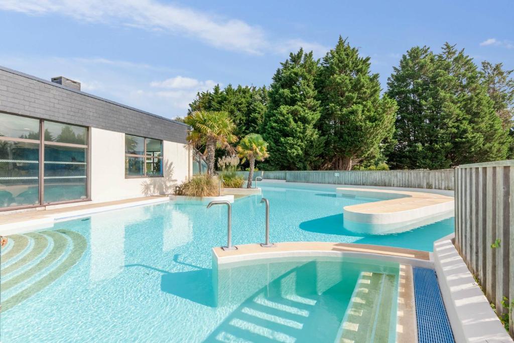 a swimming pool with blue water in a backyard at Village Pierre & Vacances Normandy Garden in Branville