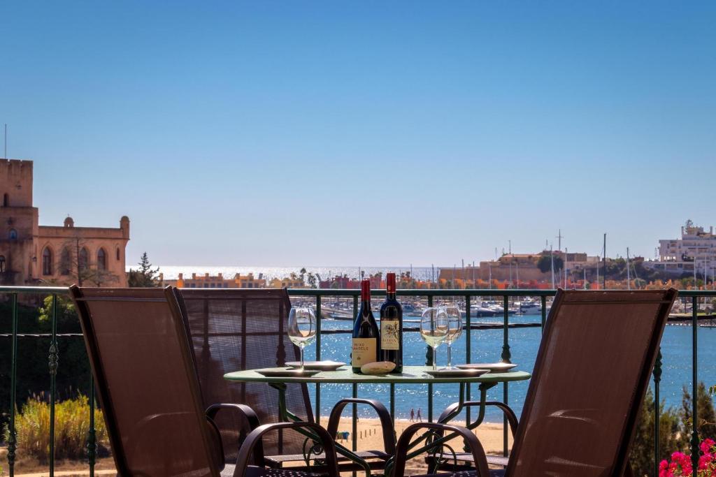 a table with two glasses of wine on a balcony at Front line townhouse Face la mer in Ferragudo luxury sea views in Ferragudo