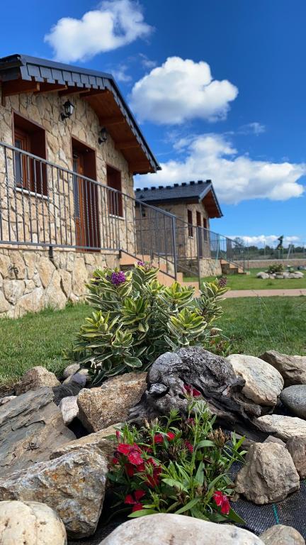 uma casa de pedra com um jardim de flores e rochas em El naval de la Parra II em Sejas de Sanabria