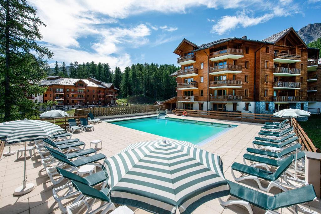a swimming pool with lounge chairs and a hotel at Résidence Pierre & Vacances l'Albane in Vars