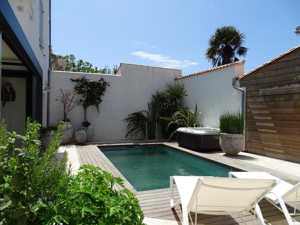 een zwembad in een achtertuin met twee witte stoelen bij Maison Le Clos Neraud avec piscine et SPA in Saint-Martin-de-Ré