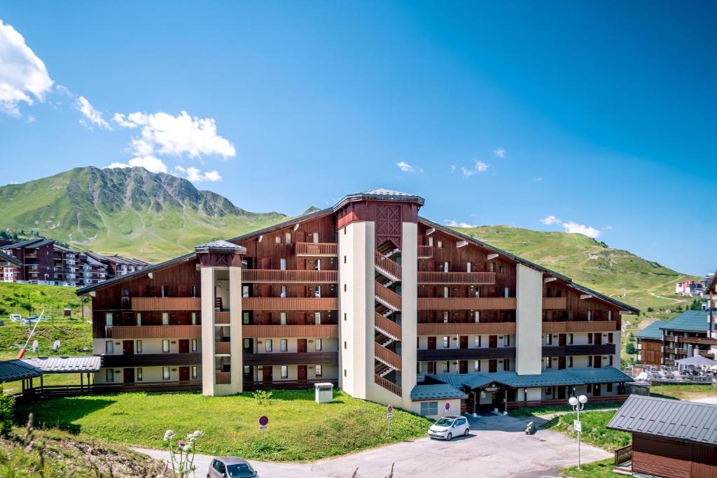 a large building with mountains in the background at Résidence Pierre & Vacances Le Mont Soleil in La Plagne
