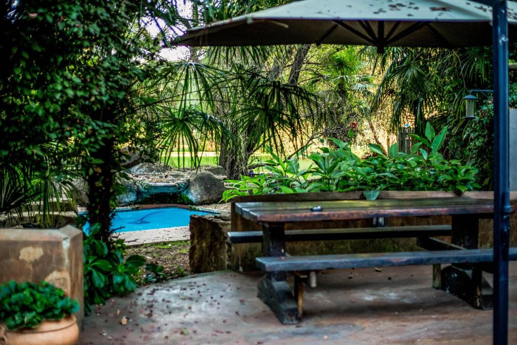 a picnic table with an umbrella next to a pool at Winterton Country Lodge @ Rose Cottage in Winterton