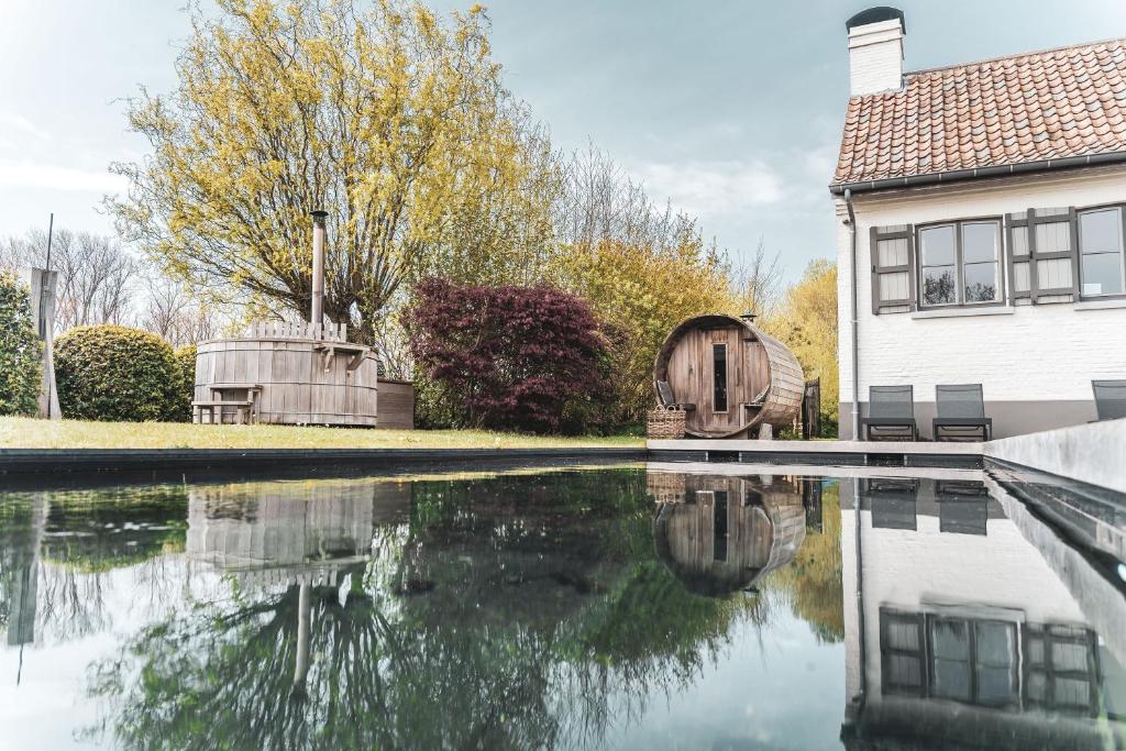 a house and a pool of water in front of a house at B&B Extra Verte in Jabbeke