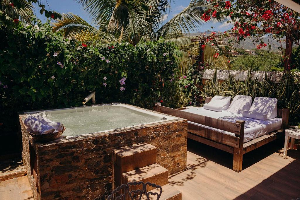 a bath tub in a garden with a couch and a chair at Hotel Kalma in Santa Fe de Antioquia