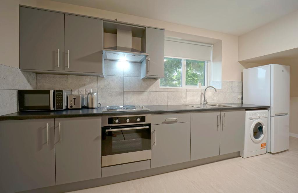 a kitchen with stainless steel appliances and a white refrigerator at Alpha Lofts, Huddersfield in Huddersfield