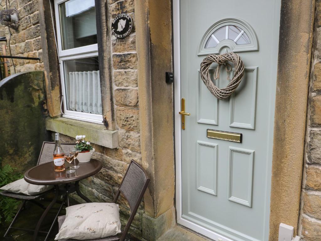 una puerta a un patio con una mesa y una corona en Bell Cottage, en Holmfirth