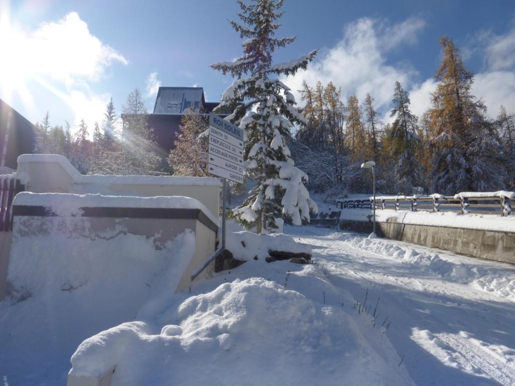 un patio cubierto de nieve con un árbol cubierto de nieve en Aurore 554, en Le Sauze