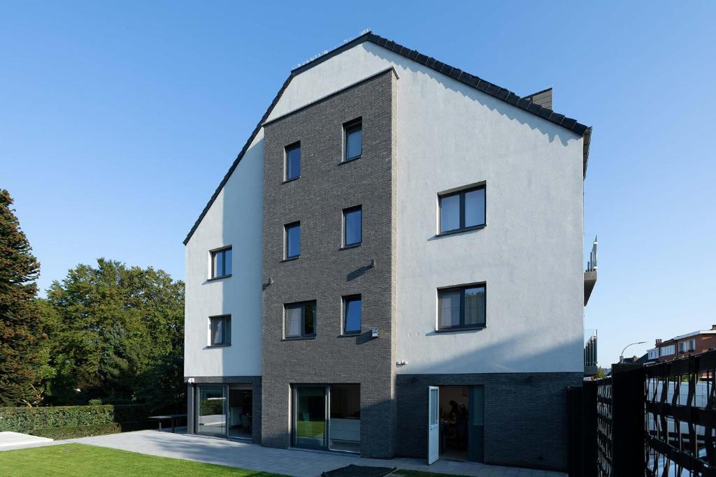 een hoog wit gebouw met een zwart dak bij BEUKENHOUSE in Drogenbos