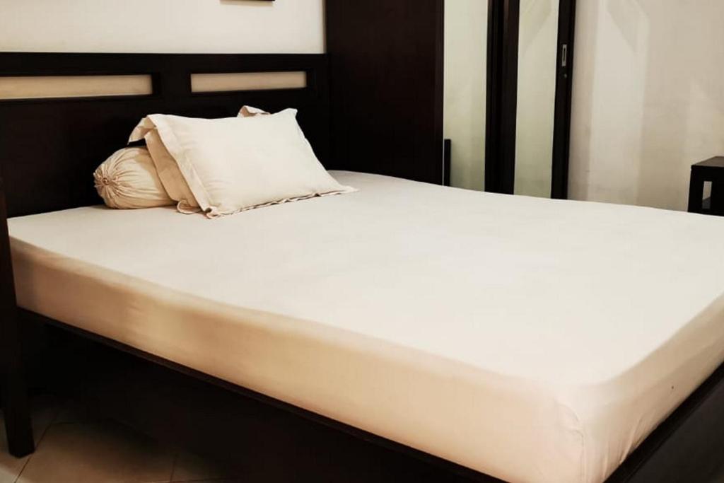 łóżko z białą pościelą i poduszkami w obiekcie Dinnar Homestay Gayungan Mitra RedDoorz w mieście Ngawinan