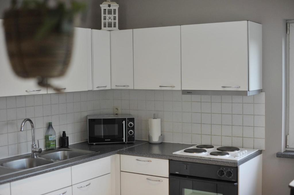 La cuisine est équipée de placards blancs, d'un évier et d'un four micro-ondes. dans l'établissement Pops Holiday Home, à Ypres