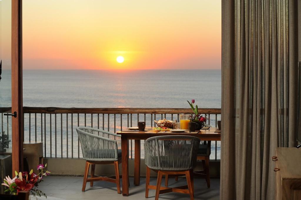 uma mesa e cadeiras numa varanda com um pôr-do-sol em Hear the waves! Amazing beachfront condo with unbeatable views! em San José del Cabo