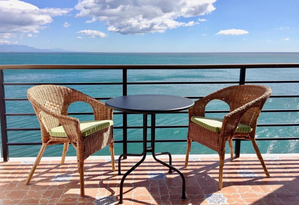 dwa krzesła i stół na balkonie z widokiem na ocean w obiekcie Sunny View Castillo Santa Clara w mieście Torremolinos