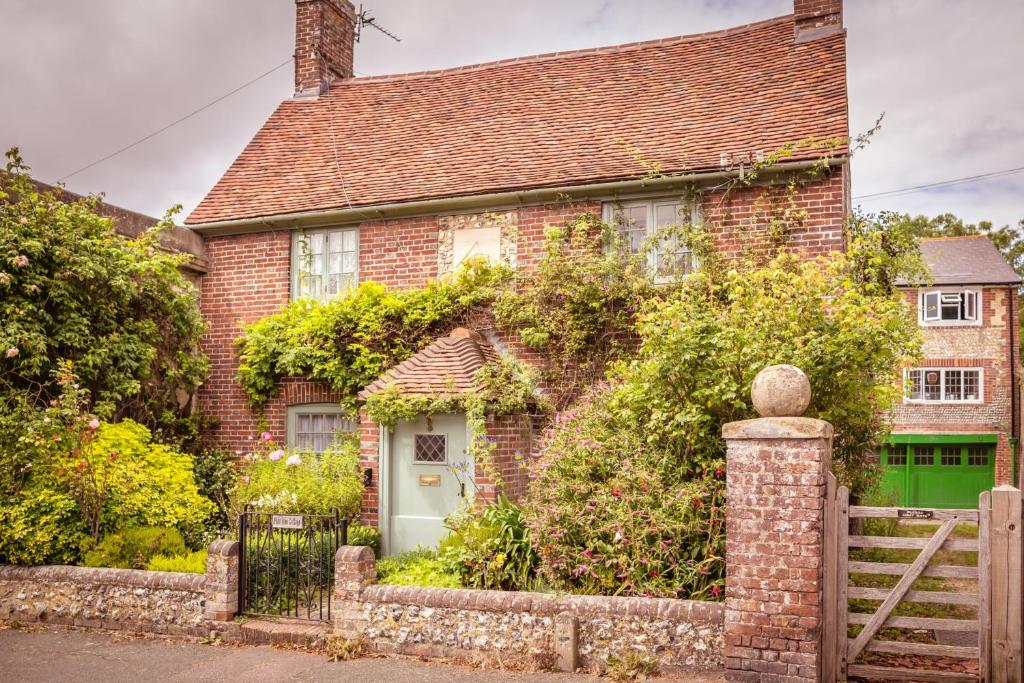 a brick house with a green door and a fence at Pear Tree Cottage in Ratton Village