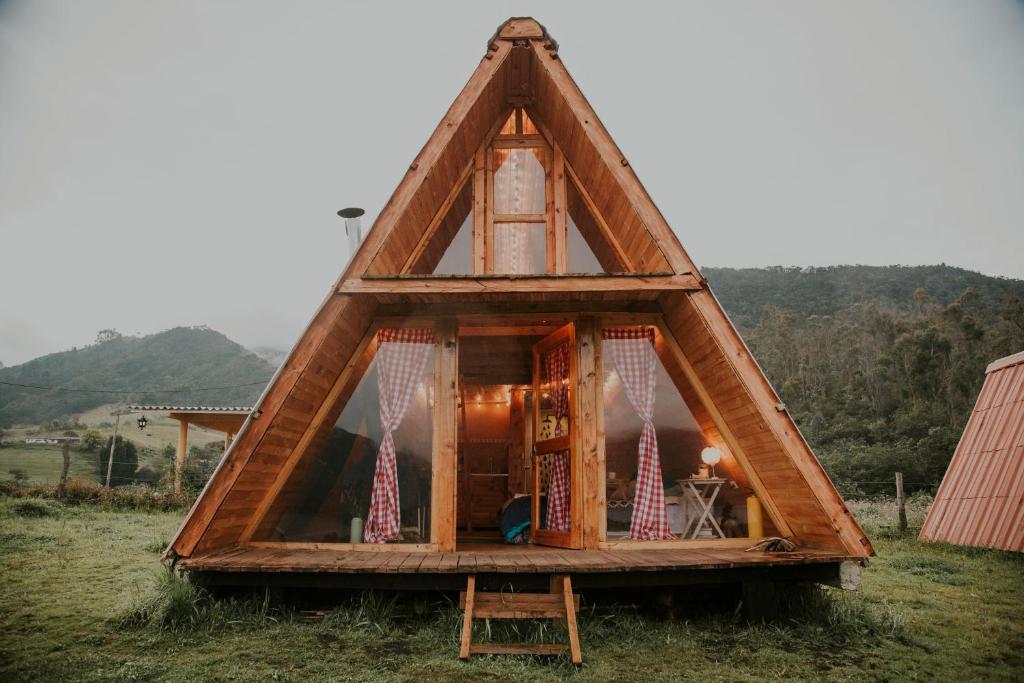 una casa marco con una ventana en un campo en Glamping y cabañas en Neusa Cundinamarca, en La Esperanza