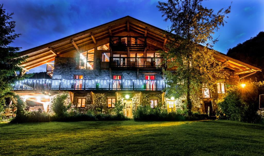 una gran casa de madera con un patio iluminado por la noche en Le Chalet De Thalie en Bourg-Saint-Maurice