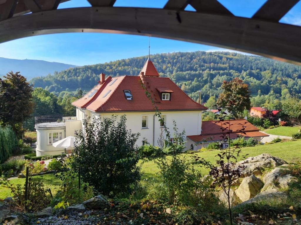 ein Haus mit rotem Dach auf einem Feld in der Unterkunft Pałacyk Szklarska in Piechowice