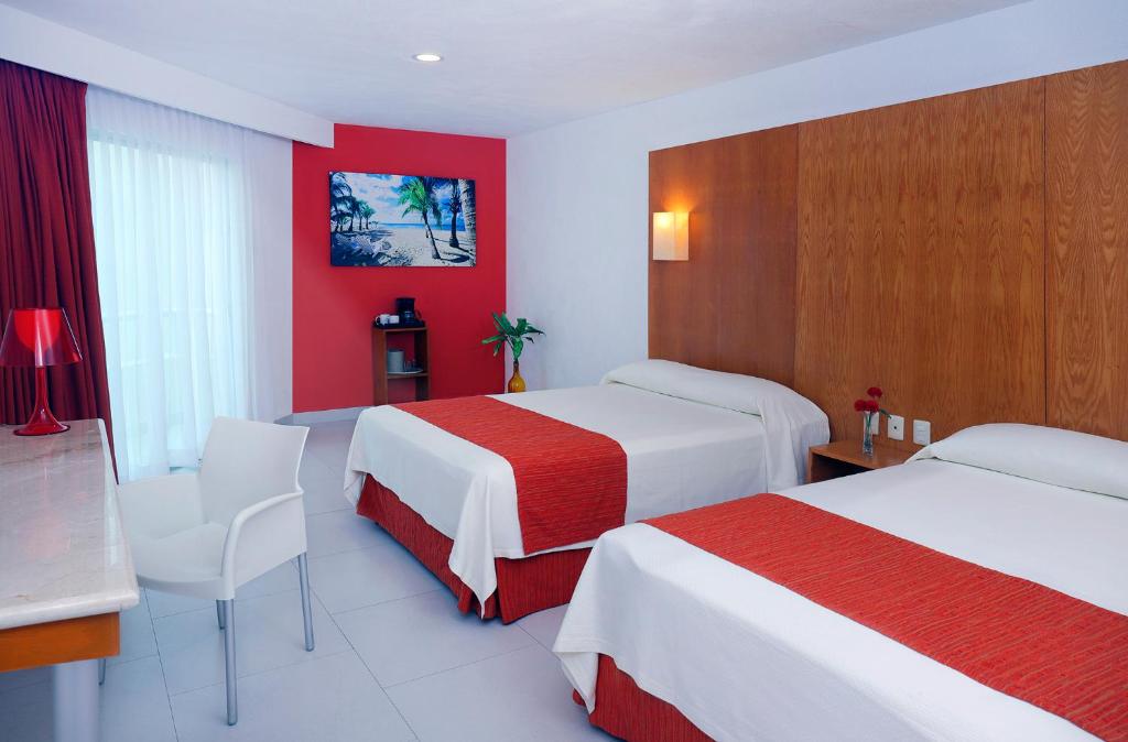 a hotel room with two beds and a red wall at Adhara Express in Cancún
