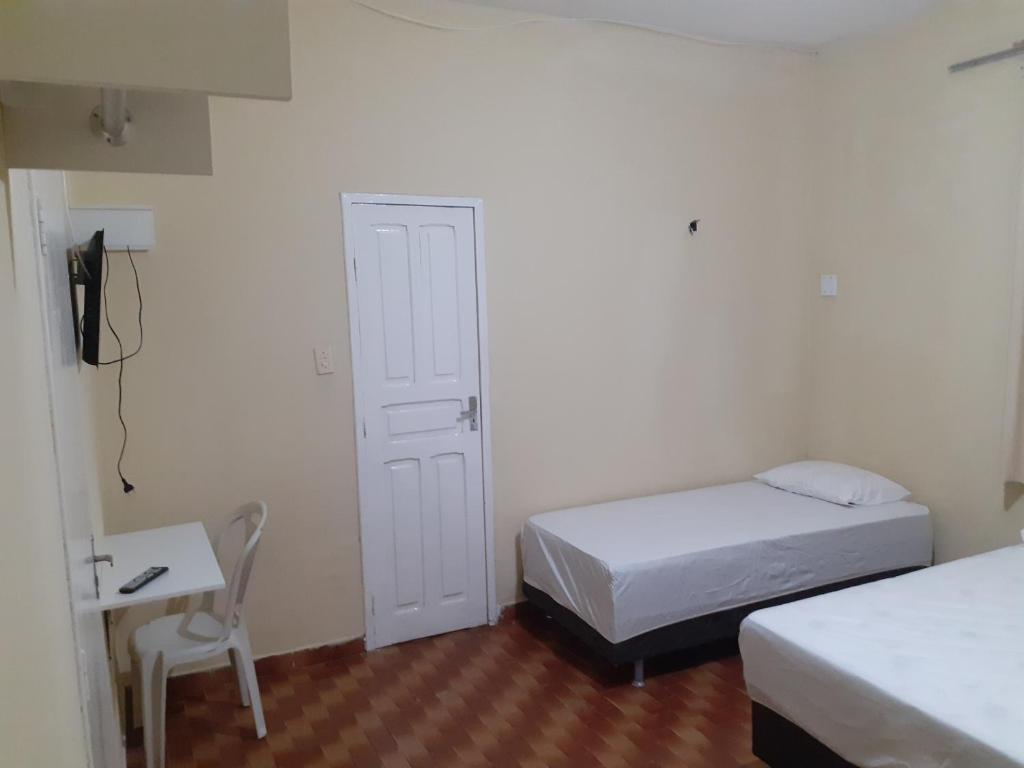 a bedroom with two beds and a desk and a chair at Hostel Parquelândia in Fortaleza