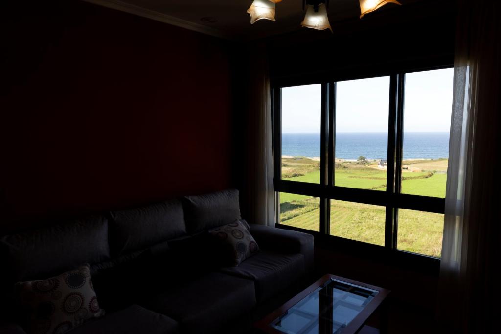 a living room with a couch and a view of the ocean at Playa de Llas in Foz