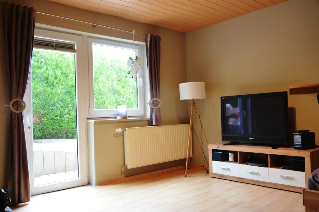 a living room with a television and a large window at Ferienwohnung im Storkenbusch in Beckingen