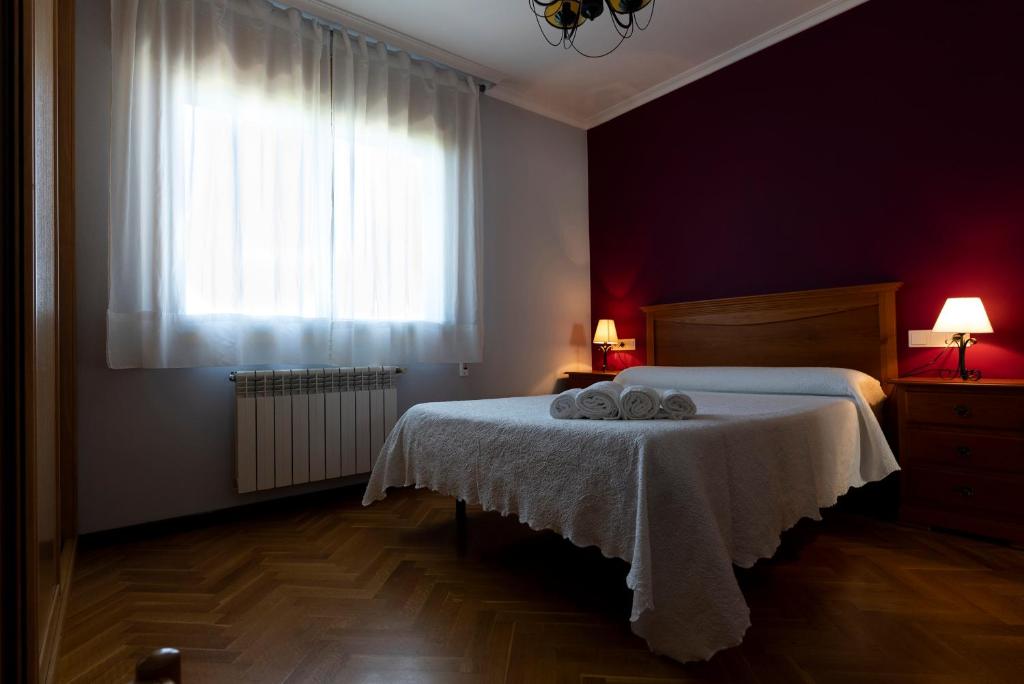 a bedroom with a bed with a white blanket and a window at Playa de Llas in Foz