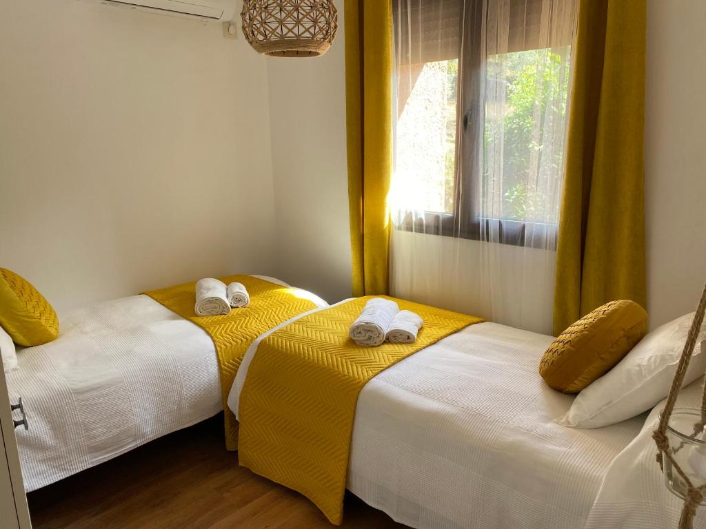 1 dormitorio con 2 camas con sábanas amarillas y ventana en Apartamento rural Prunus avium, en Cambrón