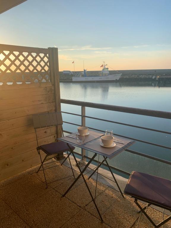 a table and chairs on a balcony with a boat in the water at Évasion à Deauville in Deauville