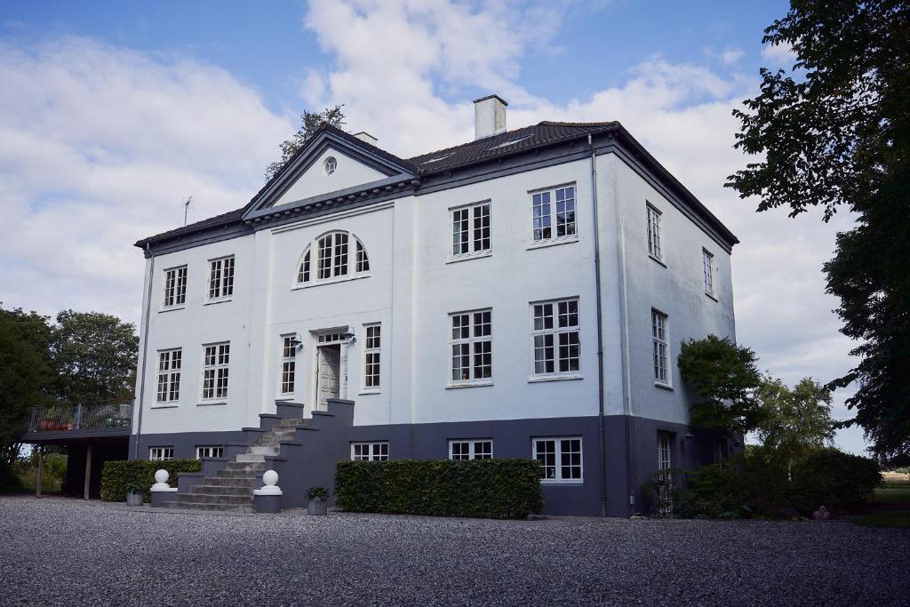 Un grand bâtiment blanc avec des escaliers se trouve juste devant. dans l'établissement Enkesædet Bollegård, à Ørsted