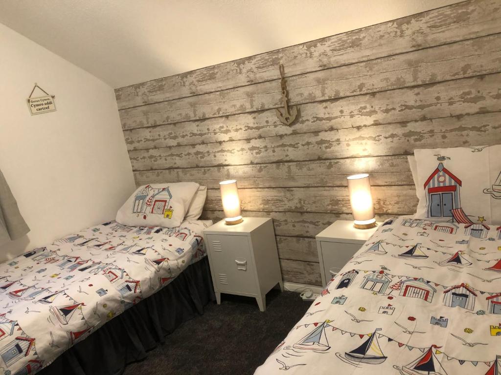 um quarto com 2 camas e 2 candeeiros em mesas de cabeceira em Gwêl y Fenai em Y Felinheli