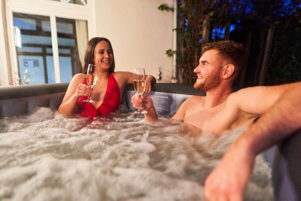 un hombre y una mujer sentados en una bañera con copas de champán en Entspannung Pur, en Herford