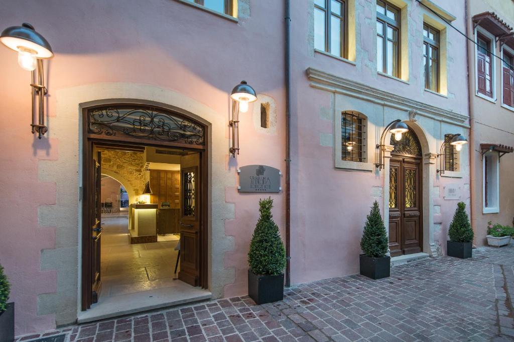 un bâtiment rose avec une porte et deux potiers dans l'établissement Serenissima Boutique Hotel, à La Canée