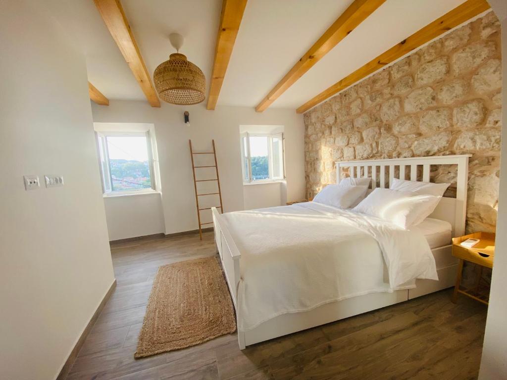 a bedroom with a white bed and a stone wall at Villa Piscitelli in Cavtat