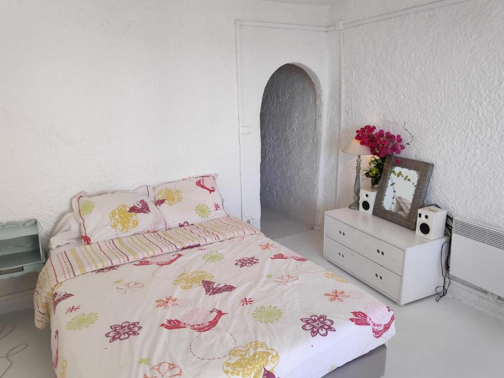 a bedroom with a bed and a dresser with a bedspread and flowers at Fisherman's View in Bages