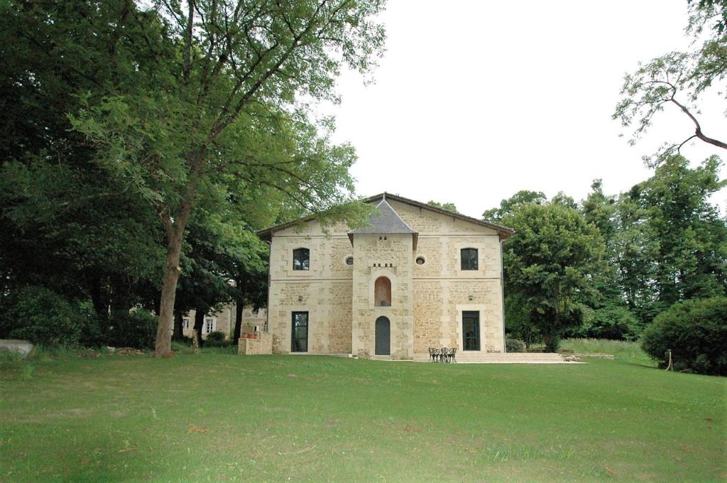 um velho edifício de pedra num campo de relva em Gîte de charme à 15mn de Bordeaux Autonomie 100% em Camblanes-et-Meynac
