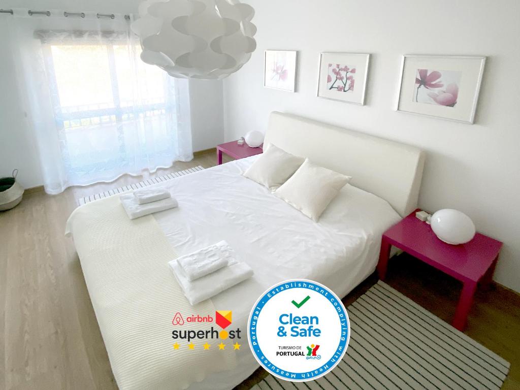 una camera da letto con un letto bianco, due tavoli e un lampadario a braccio di Apartment Castelo Branco - Portugal a Castelo Branco